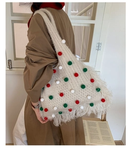 Detail view of large knit tote bag with festive pom-poms and long fringe tassels