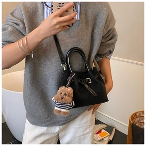 Détail du sac seau noir avec texture en cuir et pendentif ours en peluche mignon décoratif