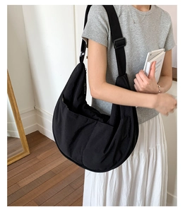 Detail of black nylon crossbody bag with three outer pockets and adjustable strap