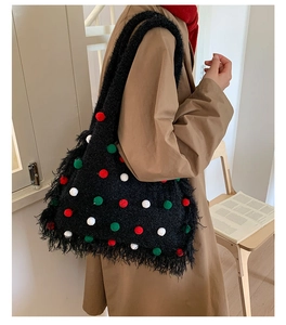 Detail of black knit tote bag with festive 3D pom-poms and fringe tassels on a model