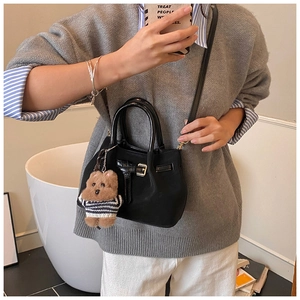 Détail du sac seau noir avec poignées en cuir verni et un charmant petit ours en peluche