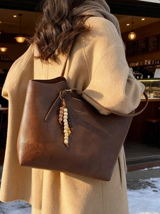 Borsa tote vintage marrone scuro con ciondolo a perline indossata da modella