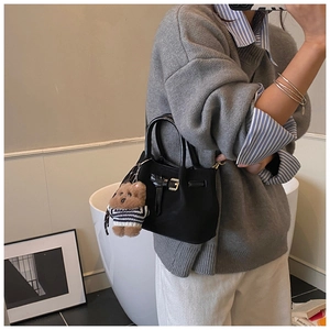 Détail du sac seau noir en cuir mat avec pendentif ours et boucle métallique