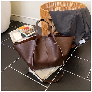 Macro detail of dark brown leather tote bag with side rivets and dual handle design
