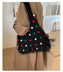 Detail of Christmas themed black knitted tote bag with colorful pom-poms and fringe