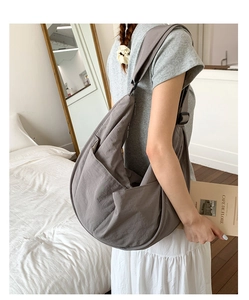 Detail of dark grey nylon hobo bag side pocket and adjustable wide shoulder strap on model