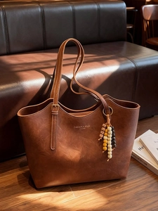 Borsa tote vintage marrone con ciondolo di perline colorate su un divano in pelle
