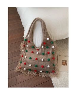 Detail of a khaki knit tote bag with colorful pom-poms and fringe edge details