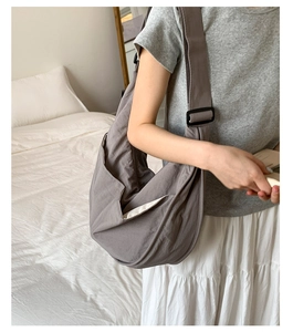 Detail view of grey nylon dumpling bag with adjustable wide strap and wrinkled texture
