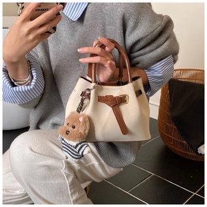 Détail du mini sac à main crème avec poignées marron et charmant pendentif chien en peluche