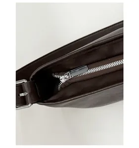 Details von silbernen Beschlägen und glattem Reißverschluss an brauner Leder-Beuteltasche
