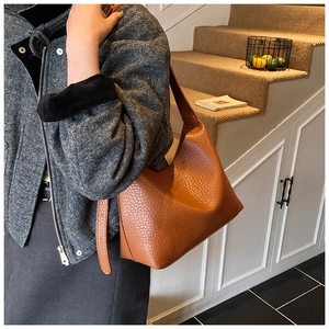 Close-up of caramel lychee grain leather handbag styled with a grey wool coat