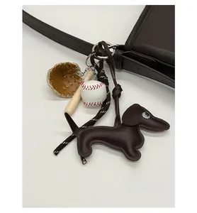 Detail eines Dackel-Taschenanhängers mit Baseball und Schläger an brauner Ledertasche