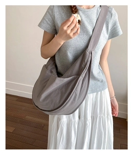 Close-up of a grey nylon dumpling bag showing large capacity and wide shoulder strap