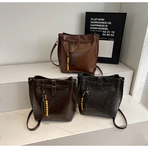 Vue détaillée des sacs seaux vintage en marron et anthracite avec pompons et perles en bois