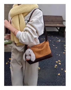 Detail of pleated caramel dumpling bag with plush rabbit charm in autumn park setting