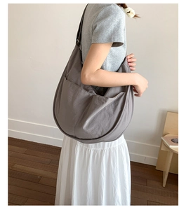 Detail of grey nylon crossbody tote bag showing large side pockets and crescent shape