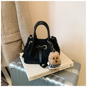 Détail du sac seau noir avec empiècement mat et un porte-clés ours en peluche marron