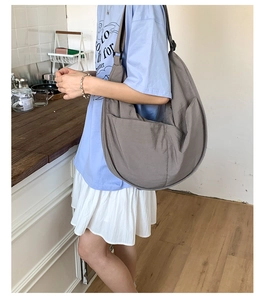 Side view of dark grey nylon crescent bag with wide shoulder strap and side pocket