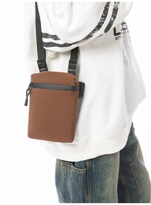 Detail of a brown nylon crossbody bag with adjustable strap and waterproof zipper pocket