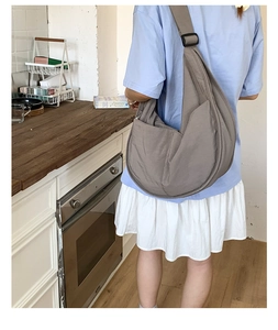 Detail of dark grey nylon crescent bag showing wide shoulder strap and side pocket detail