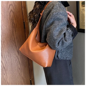 Close-up of brown pebbled leather hobo bag worn over the shoulder in a vintage room
