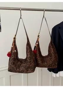 Retro paisley and leopard print tote bags with fuzzy pom-pom charms in close-up detail