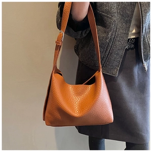 Detailed shot of an adjustable shoulder strap with silver buckle on a brown tote bag