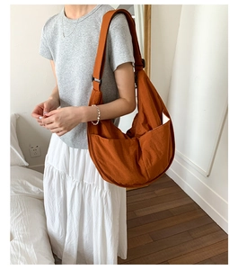 Detail of adjustable strap and buckle on orange nylon crescent bag in lifestyle setting