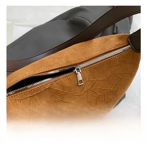 Detail showing high-quality silver metal zipper and textured brown fabric on shoulder bag
