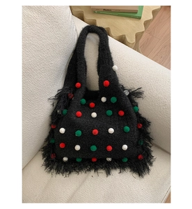 Detail shot of black knitted tote bag with colorful pom-poms and fringe accents