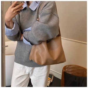 Detailed close-up of brown textured leather hobo bag worn on shoulder for daily styling