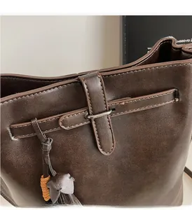 Gros plan d'un sac seau marron vintage avec boucles argentées et pompon en cuir