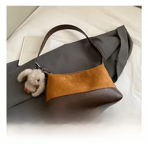 Detail view of caramel pleated patchwork shoulder bag with a plush rabbit charm