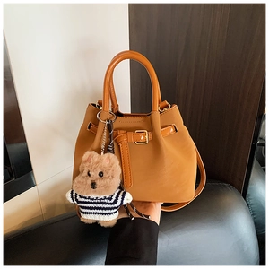 Détail du sac seau camel avec poignées rondes et charmant petit ours en peluche attaché
