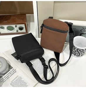 Detail of minimalist nylon crossbody bags in black and dark brown with adjustable straps
