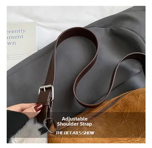 Detail of embossed brown leather bag featuring adjustable strap with silver buckle