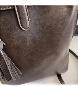 Détail d'un sac seau vintage marron avec texture cuir et pompons à franges latéraux