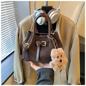 Détail du sac seau en cuir marron foncé avec boucle rétro et breloque en peluche
