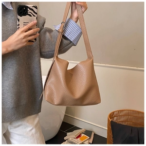 Detail of brown pebbled leather tote bag featuring an adjustable shoulder strap and texture