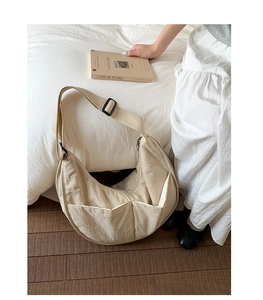 Detail view of large cream nylon crescent bag with wide strap and functional front pockets