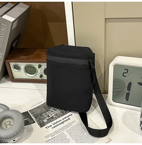 Close-up of a black nylon crossbody phone bag styled with vintage urban travel accessories