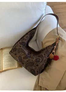 Detail of retro dark brown paisley shoulder bag with plush pendants on a soft sofa