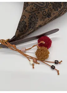 Detail of vintage tote bag featuring brown print fabric and colorful ethnic charms