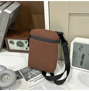 Detail of a brown crossbody bag featuring black waterproof zipper and wide nylon strap