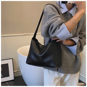 Close-up of black lychee grain leather shoulder bag with wide strap for daily commute