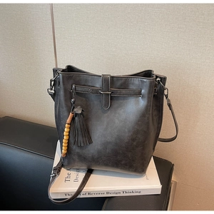 Détail du sac seau anthracite avec pompons en cuir et perle en bois décorative