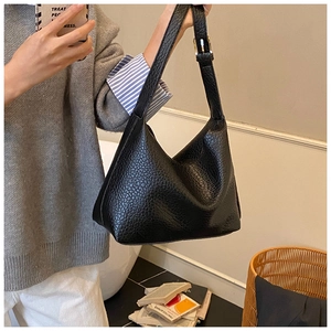 Close-up of black grainy leather hobo bag featuring an adjustable metal buckle strap