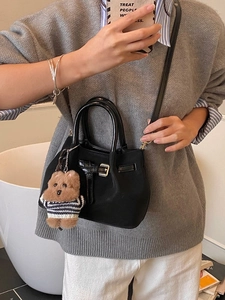 Sac seau noir chic avec pendentif ours, porté par un mannequin en style décontracté