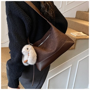 Detail of dark brown pleated leather shoulder bag with plush bunny keychain charm